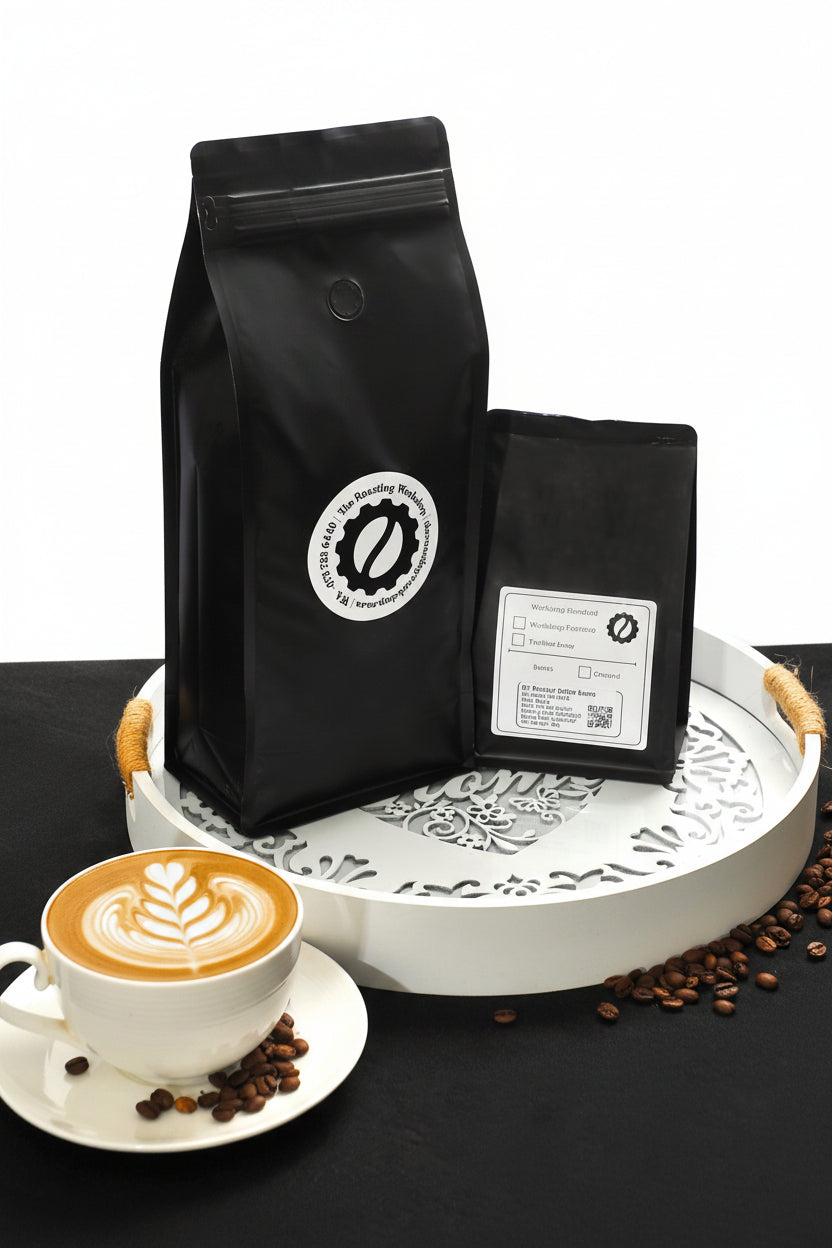 Black coffee bags with a white label, a cup of coffee beans, and a white tray on a black surface.